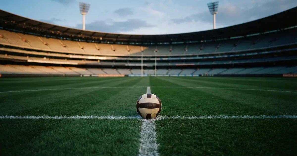 Piłka nożna leżąca na środku murawy w pustym stadionie przed meczem, rzędy siedzisk w półmroku.